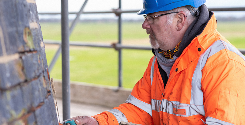 A person wearing orange PPE works on a heritage lottery funded mill restoration project