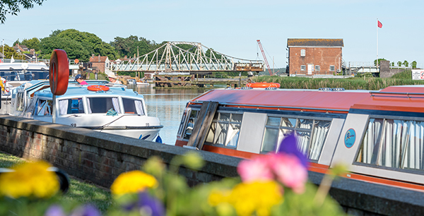 A view across the River Yare looking towards Reedham Swing Bridge, with moored boats in the foreground